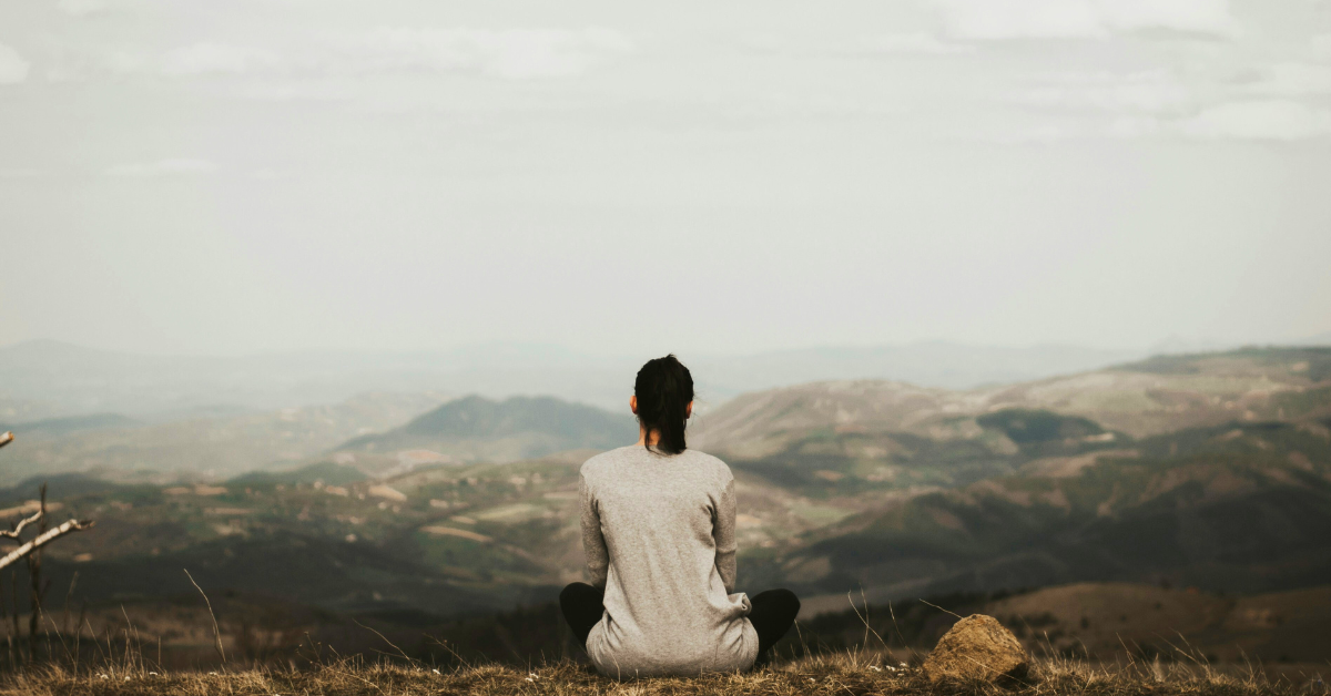 Woman sitting looking at mountain range